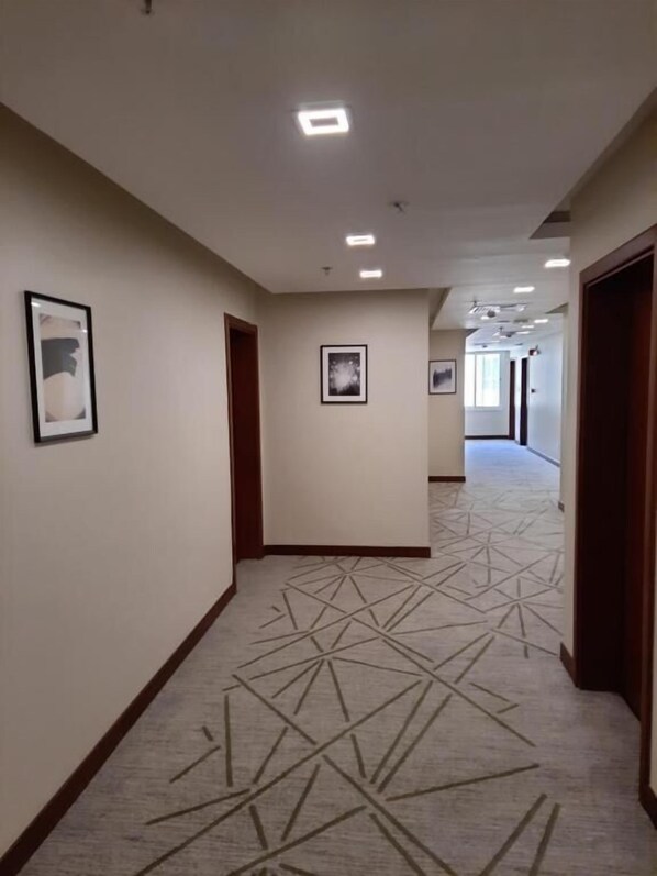 A hotel corridor with framed artwork on the walls, a patterned carpet, and recessed ceiling lights. - SBY Hotel (Jeddah)