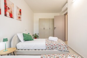 Ein Schlafzimmer mit einem Bett, einem Nachttisch, einer Lampe, einem Kleiderschrank und einer Topfpflanze.