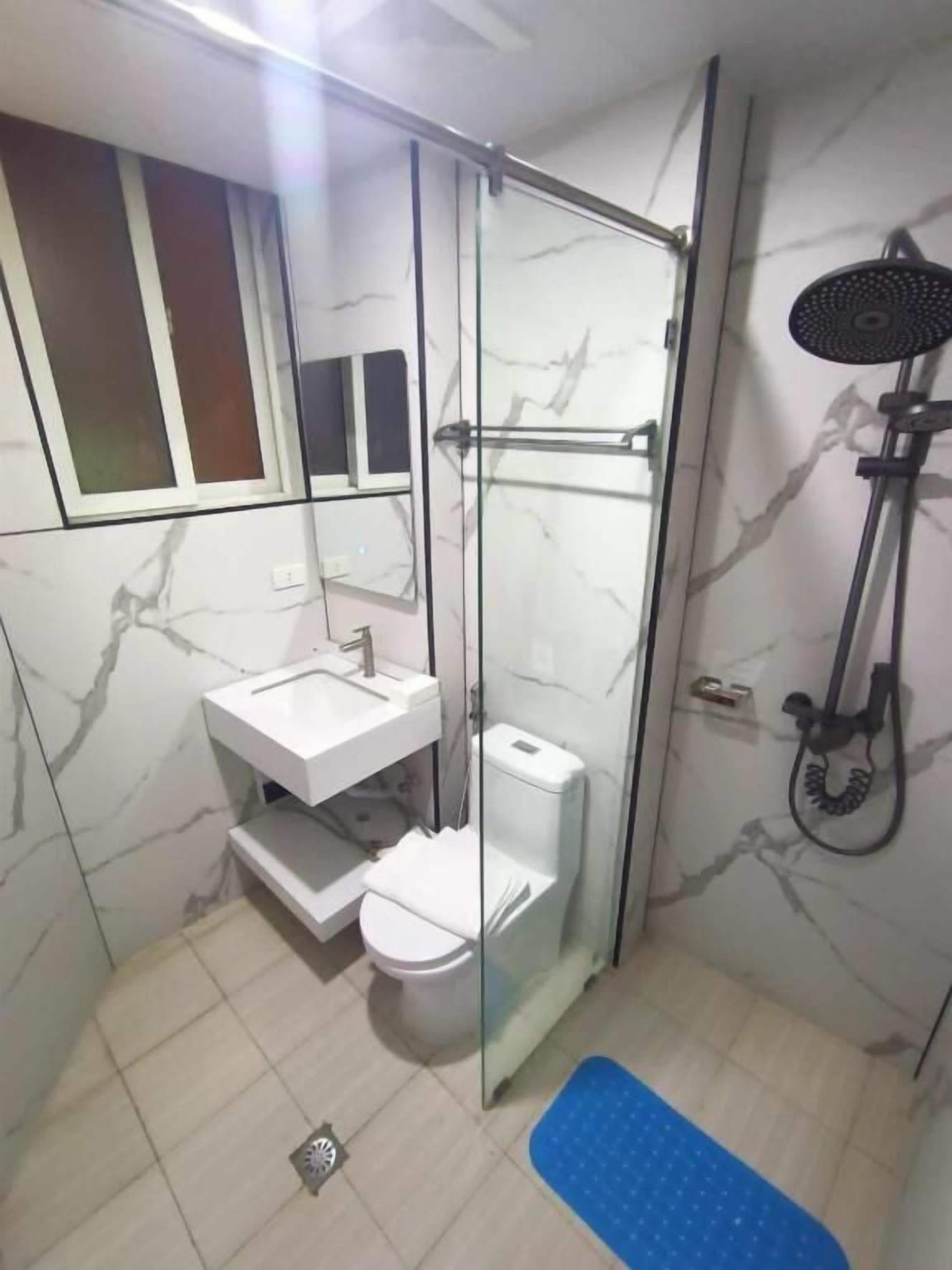 A bathroom with a glass-enclosed shower, a white sink, and a toilet.