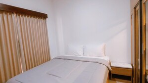 A bedroom with a bed, a nightstand, and a window with blinds. - Villa Morich (Jimbaran)