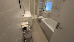 Ein modernes Badezimmer mit Badewanne, Toilette und Waschbecken.