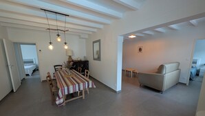 Ein geräumiger Wohnbereich mit Esstisch, Sofa und Blick auf ein Schlafzimmer.
