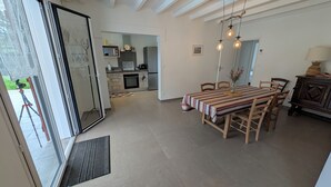 Eine moderne Küche mit Essbereich, einer Schiebetür aus Glas und einer Decke mit freiliegenden Balken.
