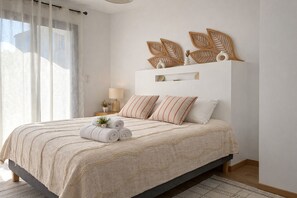 Ein Schlafzimmer mit Bett, Kissen, Nachttisch, Lampe und einer Wanddekoration.