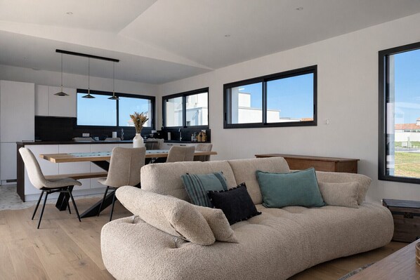 Ein modernes Wohnzimmer mit Sofa, Essbereich und Küche.