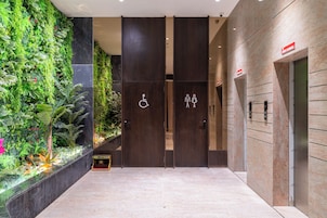 A modern lobby with a vertical garden, a reception desk, and a sign indicating a handicap accessible restroom.
