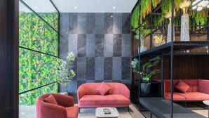 Un intérieur moderne avec un canapé rouge, une petite table et un mur vert orné de plantes.
