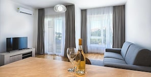 Un salon moderne avec un téléviseur à écran plat, une table à manger en bois, deux verres à vin et une bouteille de vin.