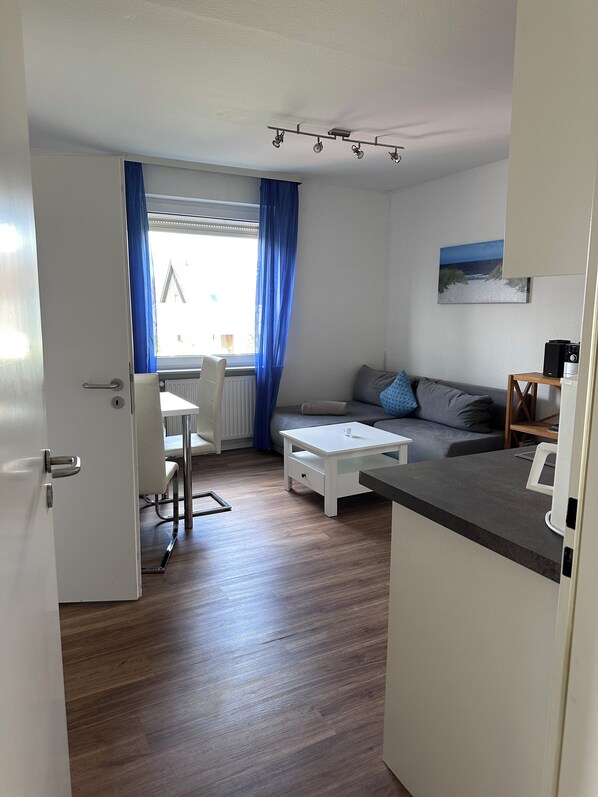 A compact living space with a kitchenette, a dining area, and a sofa.