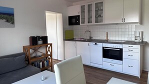 Ein kompakter Wohnraum mit Küchenzeile, Sofa, Esstisch und Bücherregal.