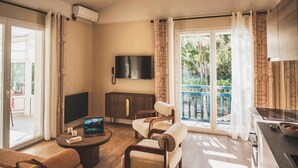 A modern living room with a flat-screen TV, a sofa, a coffee table, and a dining area with a kitchen counter. - Spacieux appt près de la plage avec terrasse (Saint-Jean-de-Luz)