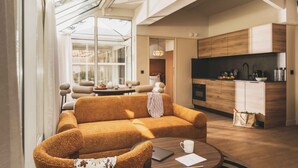 A modern living room with a sofa, a coffee table, and a kitchen area with wooden cabinets and a countertop. - Appt moderne près de la plage | Jardin privé (Saint-Jean-de-Luz)