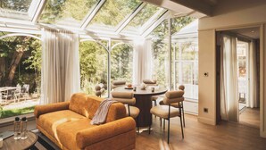 A modern living room with a sofa, round table, and chairs, large windows, and a view of the outdoors. - Appt moderne près de la plage | Jardin privé (Saint-Jean-de-Luz)