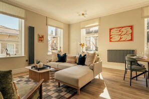 A modern living room with a sofa, coffee table, and dining area. - Beautifully Designed Central Harrogate 2 Bed Apt (North Yorkshire)