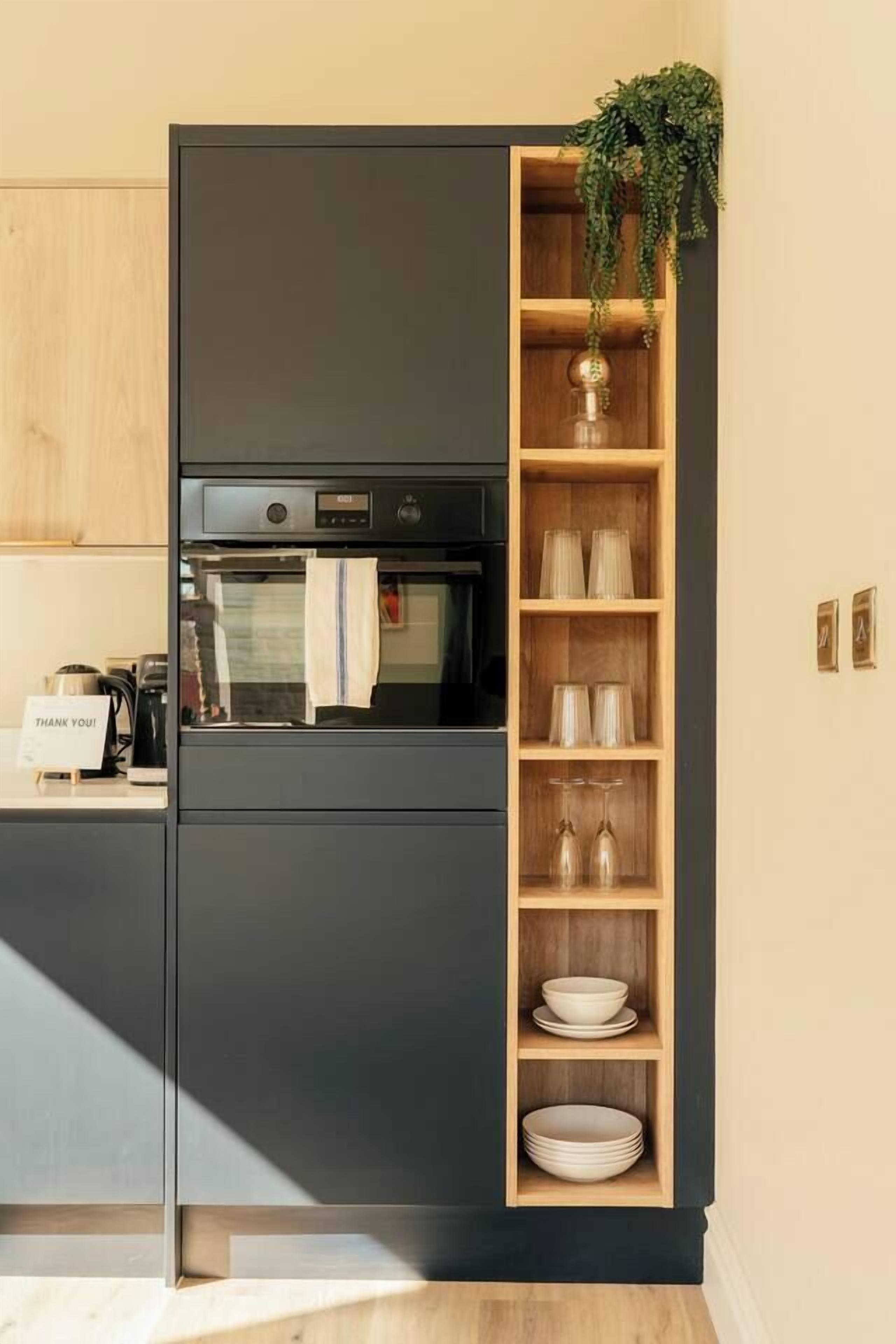 A kitchen with a built-in oven, a coffee machine, and a sign that says 'THANK YOU!'.