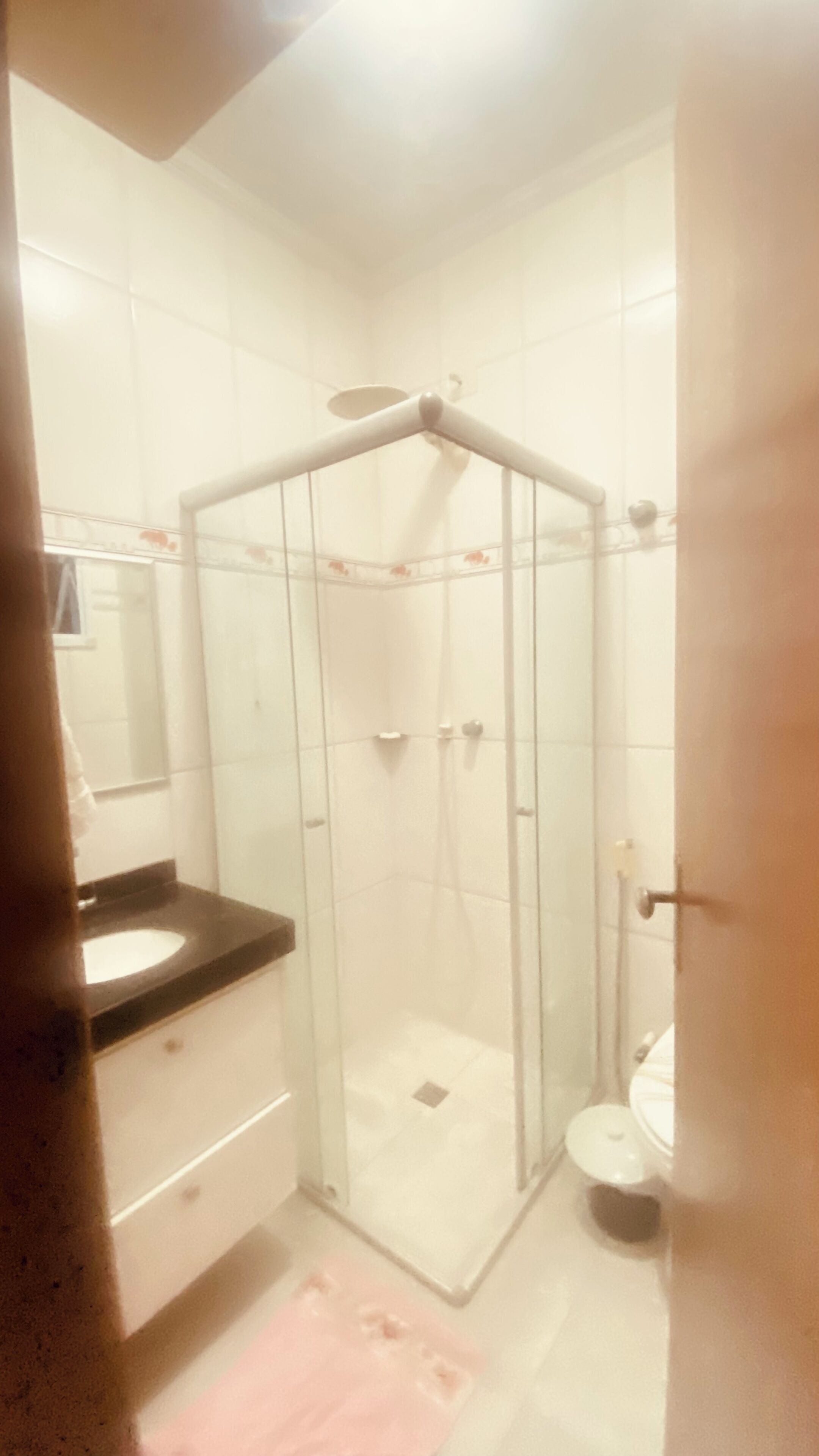 A bathroom with a glass-enclosed shower, a toilet, and a sink with a black countertop.