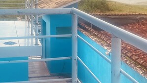 A blue building with a tiled roof, a metal railing, and a view of the sea. - Comfort and fun. Beachfront. Small pets are accepted. (Itanhaém)