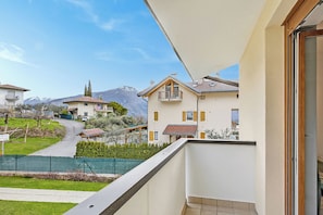 A residential building with a balcony, a mountain backdrop, and a clear sky. - Olimpia Home - Terrace Dining and Pool (Tenno)