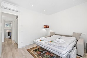 A hotel room with a bed, bedside table, lamp, and a view of the hallway. - Olimpia Home - Terrace Dining and Pool (Tenno)