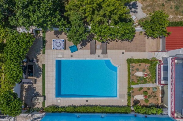 An aerial view of a swimming pool surrounded by greenery and outdoor seating.