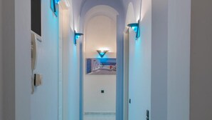 Un pasillo con suelo de baldosas, paredes blancas e iluminación azul.