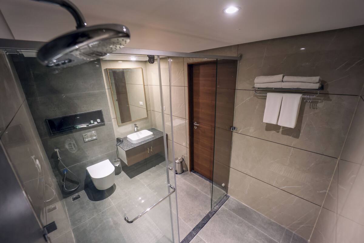 A modern bathroom with a glass shower enclosure, a sink, a mirror, and a towel rack.