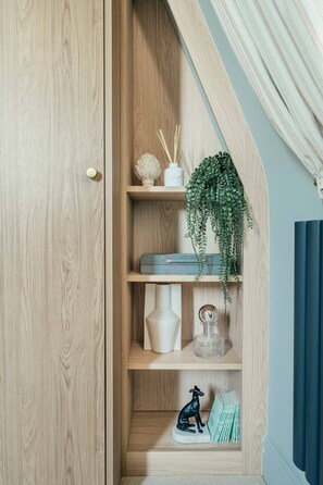 A wooden wardrobe with a hanging shelf, a small plant, and decorative items. - Stunning Central Apartment with Sky Light Views (North Yorkshire)