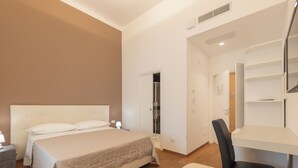 Habitación de hotel con cama, escritorio, silla, armario y baño.