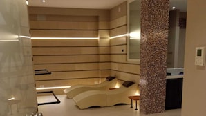 Un baño moderno con un banco curvo, una columna revestida de azulejos y un espejo.