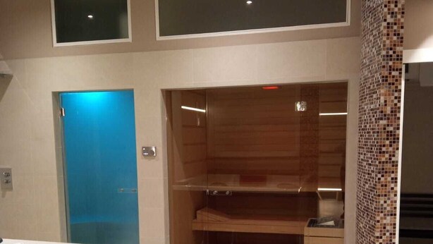 Un baño moderno con una bañera grande, zona de ducha y pared con mosaicos.