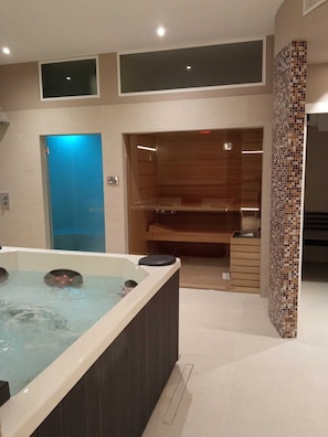 A modern bathroom with a large bathtub, a shower area, and a mosaic-tiled wall. - B&B Corte mopps (Grottaglie)