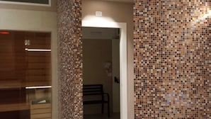 Un pasillo con pared de baldosas, un banco y una puerta que da a otra habitación.