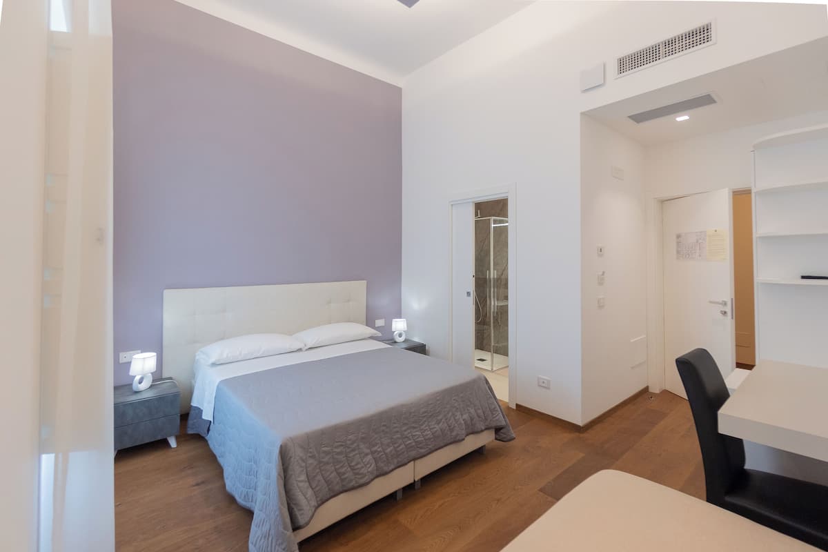 A bedroom with a bed, bedside tables, a desk, and a chair.