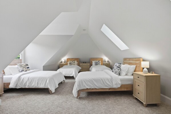 A bedroom with two beds, a nightstand, and a lamp.