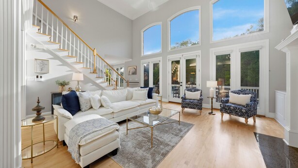 Un salon spacieux avec un escalier blanc, une grande fenêtre et un balcon.