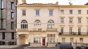 A multi-story building with a red door, a balcony, and a black car parked in front. - Paddington Station 2-Bed 4-Guest Designer Flat (London)