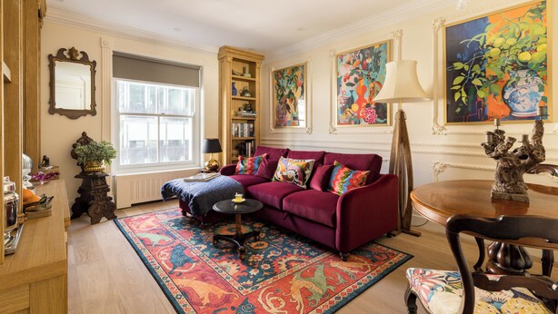A living room with a red sofa, a patterned rug, a bookshelf, and a large window. - Paddington Station 2-Bed 4-Guest Designer Flat (London)