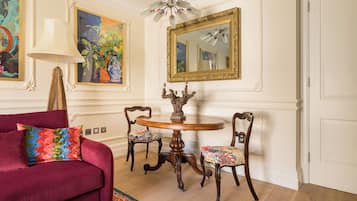 A room with a round wooden table, two chairs, a red sofa, a lamp, and a large mirror on the wall.