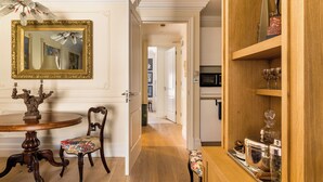 A dining area with a wooden table, chairs, a mirror, and a cabinet with glassware. - Paddington Station 2-Bed 4-Guest Designer Flat (London)