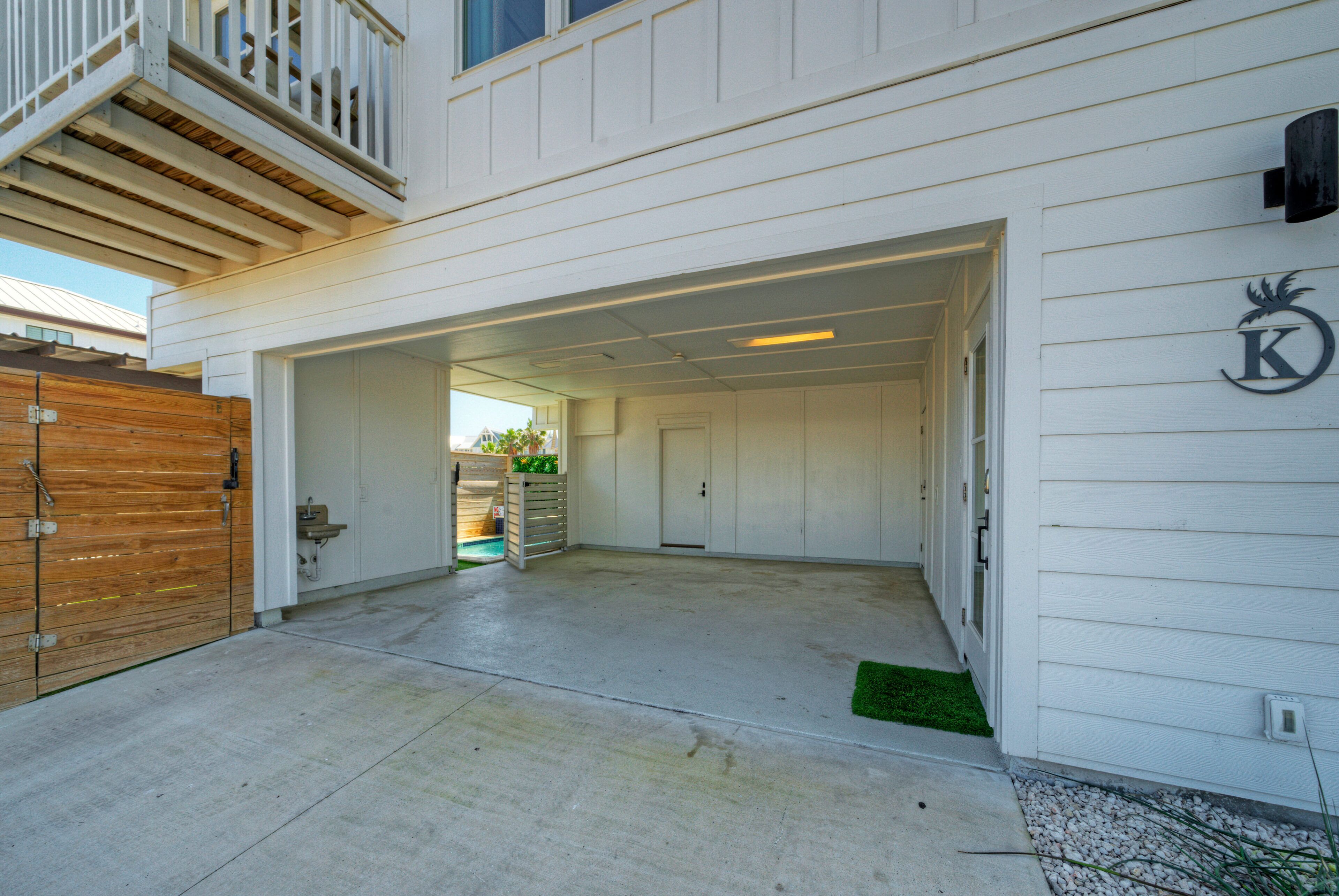 A white building with a garage door, a wooden fence, and a small green area.
