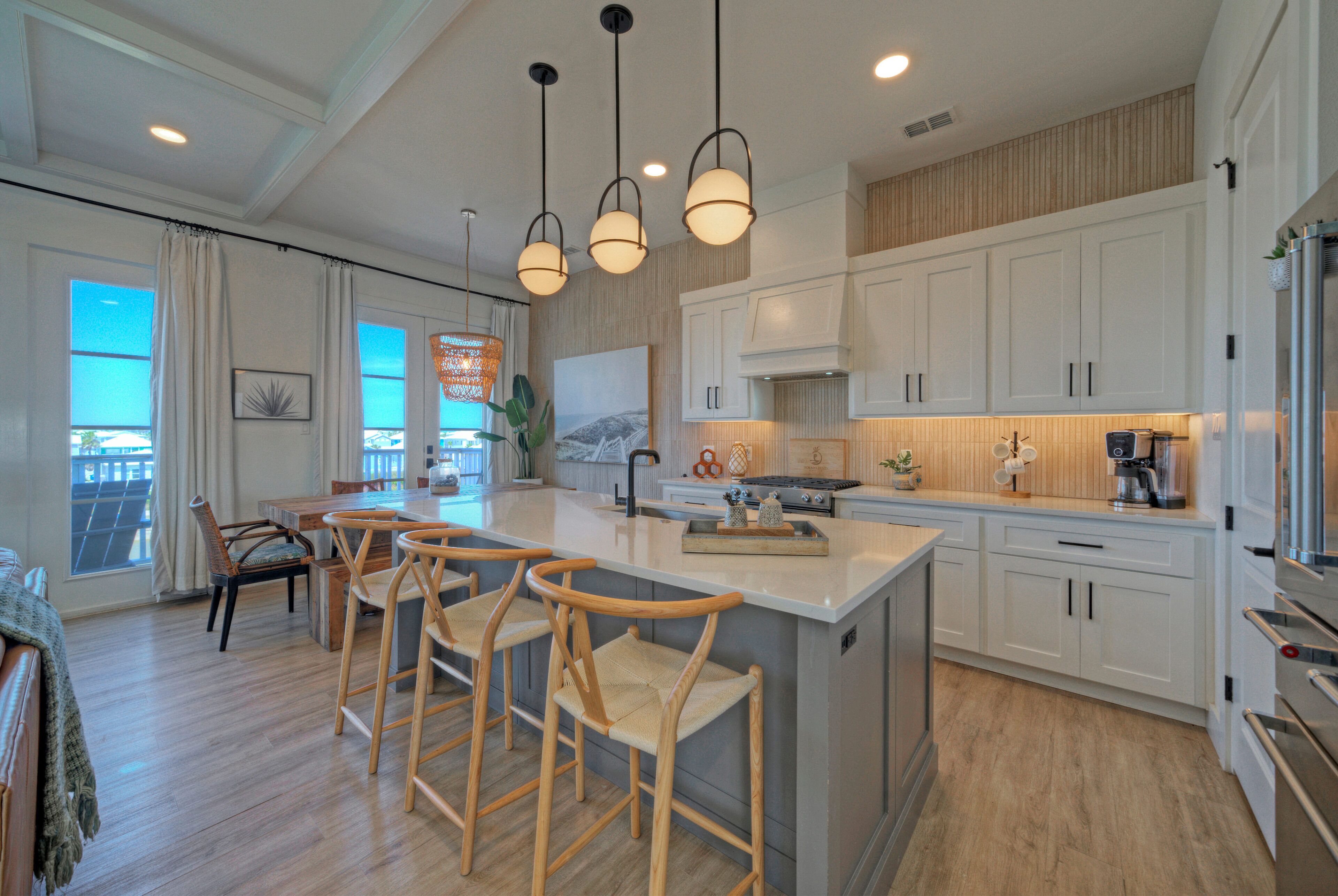 A modern kitchen with a large island, bar stools, and white cabinetry.