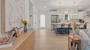 Een moderne keuken met witte kasten, een centraal eiland en hangende lampen.