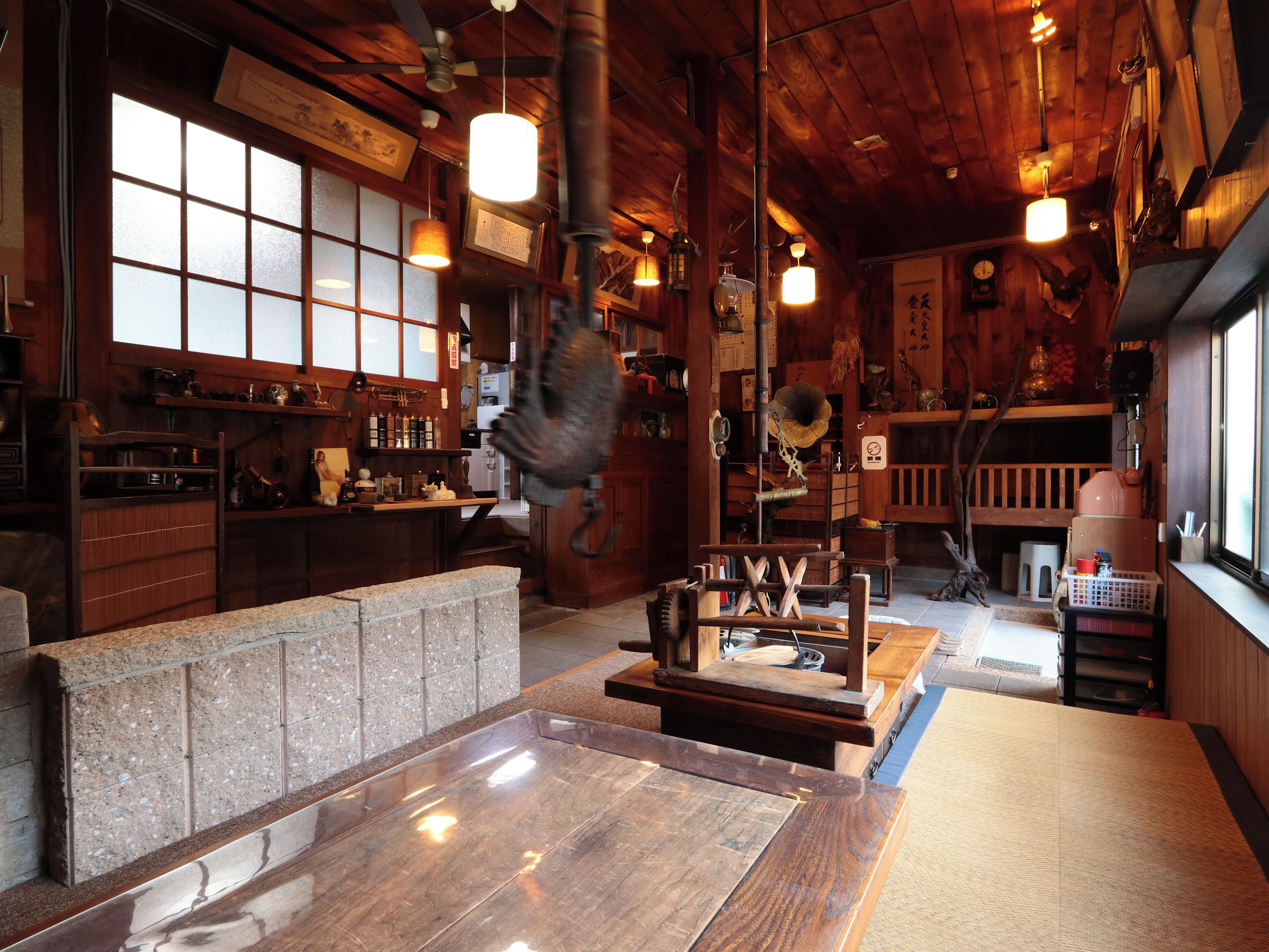 A traditional Japanese-style interior with wooden beams, tatami flooring, and a stone counter.