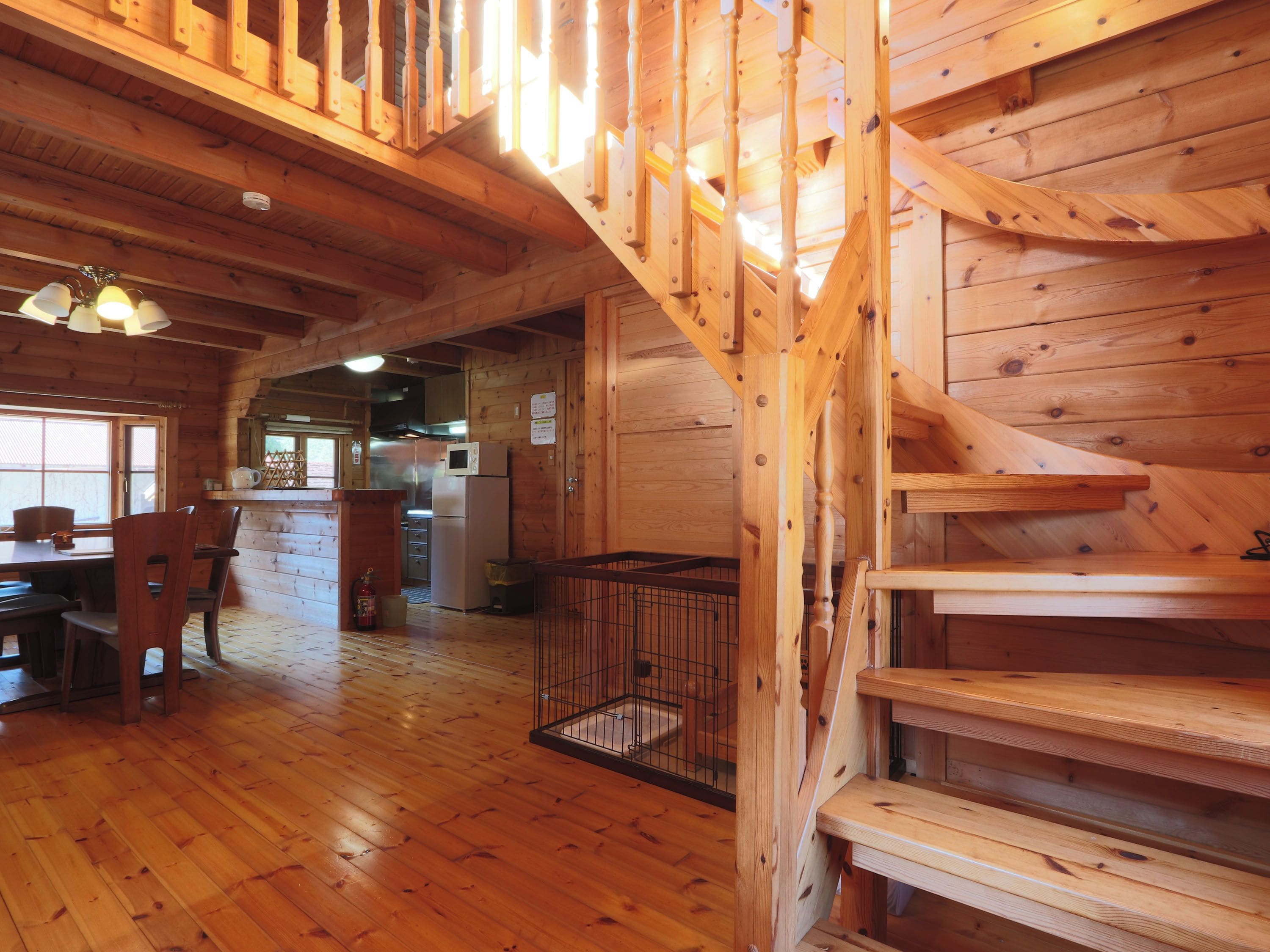 A wooden interior with a staircase, a dining area, and a kitchen.
