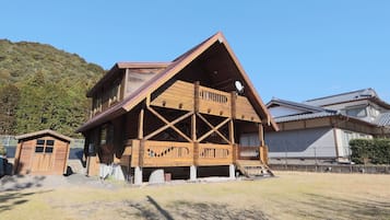 Un edificio de madera de dos pisos con un balcón y una estructura pequeña adosada.