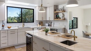 A modern kitchen with a large island, white cabinetry, and pendant lighting. - Pool + Hot Tub + Skyline Views | Hollywood Hills | Mulholland Vista Estate (Los Angeles)