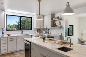 Une cuisine moderne dotée d’un grand îlot central, de meubles blancs et d’un éclairage suspendu.