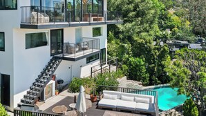 A modern two-story house with a balcony, outdoor seating, and a swimming pool. - Pool + Hot Tub + Skyline Views | Hollywood Hills | Mulholland Vista Estate (Los Angeles)