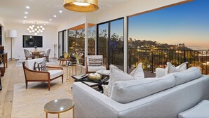 A modern living room with a sofa, armchairs, a coffee table, and a dining area with a table and chairs. - Pool + Hot Tub + Skyline Views | Hollywood Hills | Mulholland Vista Estate (Los Angeles)
