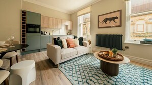 Een moderne woonkamer met een bank, een eettafel en een keuken op de achtergrond.